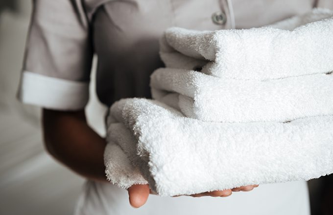 Hotel Housekeeper holding a stack of freshly washed and folded towels.