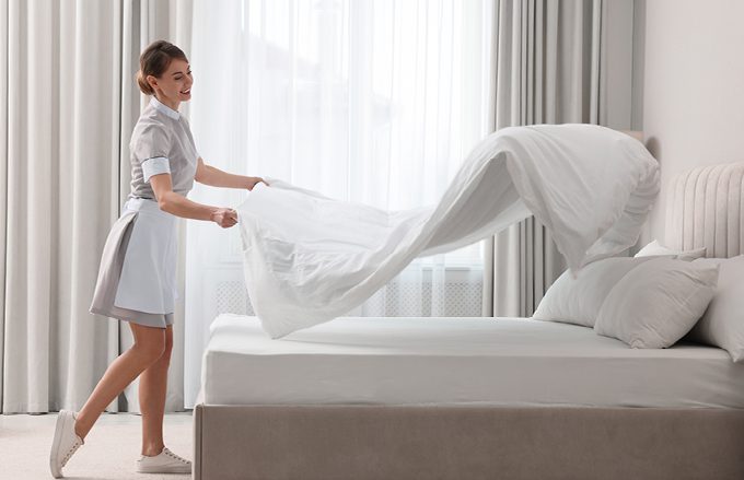 Hotel Housekeeper making a guest bed after check out.